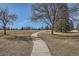 Curving concrete path through grassy area with mature trees at 7725 S Cove Cir, Centennial, CO 80122