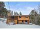 Two-story home exterior, wood siding, deck, hot tub, snowy landscape at 65 Cottonwood Dr, Evergreen, CO 80439