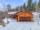 Mountain home exterior with snow-covered yard and attached garage at 65 Cottonwood Dr, Evergreen, CO 80439