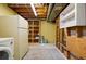 Unfinished basement space with painted walls, storage shelves, and included washer/dryer at 7065 Ingalls Ct, Arvada, CO 80003