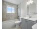 This bathroom offers a tub and shower combo with gray tile, plus a sink and vanity with a gray finish at 7065 Ingalls Ct, Arvada, CO 80003
