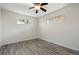 An empty bedroom with gray wood flooring, ceiling fan with light, and two windows at 7065 Ingalls Ct, Arvada, CO 80003