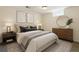 Cozy bedroom with neutral decor, comfortable bedding, modern artwork, and a round mirror above the dresser at 7065 Ingalls Ct, Arvada, CO 80003