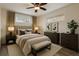 Inviting bedroom with two windows, two dressers, neutral decor, and a comfortable upholstered bench at the foot of the bed at 7065 Ingalls Ct, Arvada, CO 80003