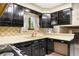 Galley kitchen featuring glossy black cabinets and tile backsplash at 9043 W Warren Dr, Lakewood, CO 80227