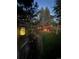 Backyard with a fire pit, pergola, and lush landscaping is illuminated by string lights for an enjoyable evening ambiance at 7264 Wembley Pl, Castle Pines, CO 80108