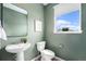 Bathroom featuring a modern pedestal sink, decorative mirror, and an ample natural light-filled window at 2054 S Upham Way, Denver, CO 80227