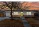 Charming single-story home with a well-manicured lawn, brick accents, and a vibrant green front door under a sunset sky at 1515 Sagrimore Cir, Lafayette, CO 80026