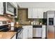Efficient kitchen featuring stainless steel appliances, white cabinets, and a neutral backsplash at 1515 Sagrimore Cir, Lafayette, CO 80026