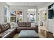 Bright living room featuring a brown leather sofa, large windows, and backyard views at 9145 Sugarstone Cir, Highlands Ranch, CO 80130
