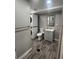 A full bathroom with a vanity sink, stacked washer dryer, gray walls, and dark vinyl plank floors at 1477 S Wright Ct, Lakewood, CO 80228