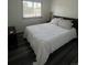 A bedroom with a neatly made bed with white patterned blanket and dark wood-style flooring at 1477 S Wright Ct, Lakewood, CO 80228