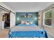 Bright bedroom with a blue accent wall, decor shelving, and large window for natural light at 4560 Flanders Way, Denver, CO 80249
