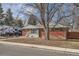 Charming brick home featuring a cozy front yard with mature trees and a small seating area at 7005 S Ash Cir, Centennial, CO 80122