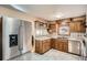 Well-lit kitchen with wood cabinets, stainless steel refrigerator, and tile flooring at 7005 S Ash Cir, Centennial, CO 80122