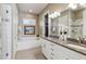 Well-lit bathroom featuring double sinks with granite countertop, bathtub, and modern fixtures at 65 Newport St, Denver, CO 80230
