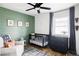 Charming Bedroom features a crib, olive green accent wall, and stylish black ceiling fan for a modern, cozy space at 873 S Raritan St, Denver, CO 80223