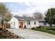 Quaint home with concrete driveway, orange door and a well-maintained lawn at 873 S Raritan St, Denver, CO 80223