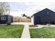 Garage and shed in the backyard featuring dark exteriors, concrete driveway and walkway, set against a lush green lawn at 873 S Raritan St, Denver, CO 80223