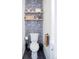 Cozy powder room with wallpaper, open shelves, and a stylish toilet and matte black fixtures at 873 S Raritan St, Denver, CO 80223