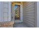 Covered porch and front door with storm door, welcome mat and brick trim at 71 Woodland Cir, Highlands Ranch, CO 80126