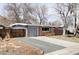 Inviting single-story home with a brick and gray facade, attached garage, and a gravel driveway bordered by brick edging at 5945 Dudley Ct, Arvada, CO 80004