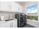 Bright laundry room featuring modern washer and dryer with sleek cabinets and a large window showcasing mountain views at 2250 Highlands Dr, Breckenridge, CO 80424