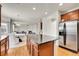 Bright, open kitchen with island, stainless steel refrigerator, and hardwood floors flowing into the living area at 13457 Locust St, Thornton, CO 80602