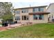 Lovely tan house with large windows overlooking a large grassy backyard with a patio, grill, and outdoor dining area at 10253 Fairgate Way, Highlands Ranch, CO 80126