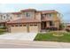 Two story home with a three car garage, brown roof, and tan and stone exterior at 10253 Fairgate Way, Highlands Ranch, CO 80126