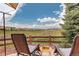 Relaxing patio area with comfortable chairs and a scenic view of the open green space beyond a rustic wooden fence at 10253 Fairgate Way, Highlands Ranch, CO 80126