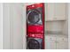 Modern laundry room featuring stacked red washer and dryer unit and white shaker cabinets at 2215 E 7Th Avenue Pkwy, Denver, CO 80206