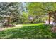 Beautiful backyard features mature trees, a lush lawn, and an outdoor patio area at 9880 E Progress Cir, Greenwood Village, CO 80111