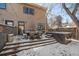 Winter backyard with a hot tub, dining set, and grill on a wooden deck, perfect for snowy outdoor gatherings at 3323 W Hayward Pl, Denver, CO 80211