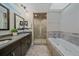 Bright bathroom featuring a double sink vanity, large tub, and glass shower at 3323 W Hayward Pl, Denver, CO 80211