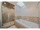 Bright bathroom showcasing a bathtub, glass shower, and skylight at 3323 W Hayward Pl, Denver, CO 80211