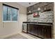 Stylish wet bar with stone backsplash, dark cabinetry, and a beverage fridge at 3323 W Hayward Pl, Denver, CO 80211