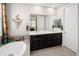 Bright bathroom features a double vanity with black cabinetry, soaking tub, and granite counters at 10185 Isle St, Parker, CO 80134