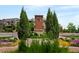 Attractive community entrance with decorative landscaping, trees, and brick monument with community logo at 10185 Isle St, Parker, CO 80134