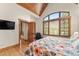 Bright main bedroom featuring a vaulted wood ceiling, floral bedding and a large arched window with wooded views at 50 Cooney Ct, Breckenridge, CO 80424