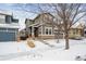 Two-story house with a stone facade, a snow-covered front yard, and mature trees at 10251 Rifle St, Commerce City, CO 80022