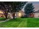 Landscaped front yard featuring lush green grass, mature trees, and a charming brick home at 2745 N Saint Paul St, Denver, CO 80205