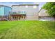 View of the home's rear exterior, showcasing a well-maintained lawn, deck, patio, and neutral siding at 10235 Rustic Redwood Ln, Highlands Ranch, CO 80126