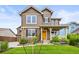 Charming two-story home with stone accents, a landscaped yard, and a welcoming front porch and yellow door at 10235 Rustic Redwood Ln, Highlands Ranch, CO 80126