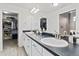 Bright bathroom with double sinks, white cabinets, and a large mirror reflecting the walk-in closet at 385 Poppy View Ln, Erie, CO 80516