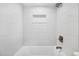 Clean bathroom with white subway tiles, a shower-tub combo, and a built-in shelf for storage at 714 Sedge Way, Lafayette, CO 80026