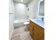 Well lit bathroom features a shower and tub with bright white tile surround and wood grain tile flooring at 714 Sedge Way, Lafayette, CO 80026