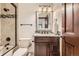 Bathroom featuring a modern vanity, stone countertop, decorative backsplash, and a shower-tub combo at 5390 S Geneva St, Englewood, CO 80111