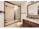 Bathroom featuring a modern vanity, stone countertop, decorative backsplash, and glass enclosed shower-tub combo at 5390 S Geneva St, Englewood, CO 80111