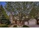 Beautiful exterior of a two-story home with stone and brick accents, a large tree, and an attached two-car garage at 5390 S Geneva St, Englewood, CO 80111